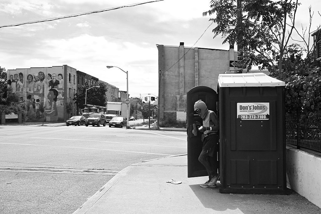 A man coming out of a portable toilet.