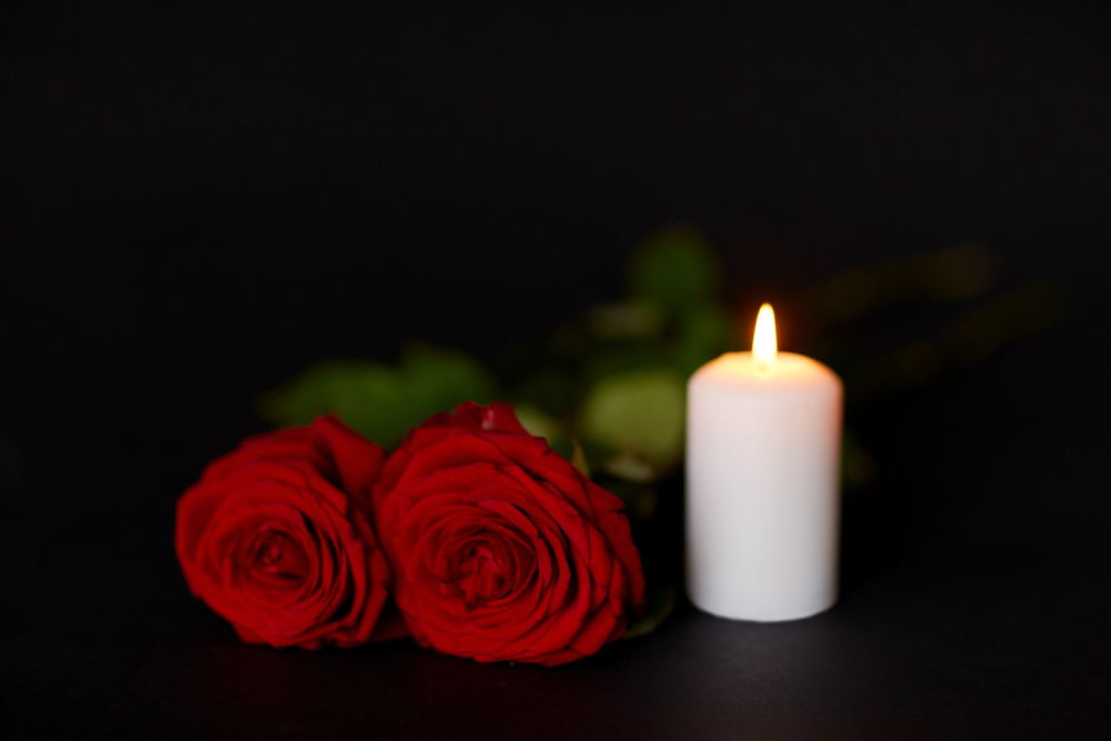 Red roses and burning candle over black background — Stock Image